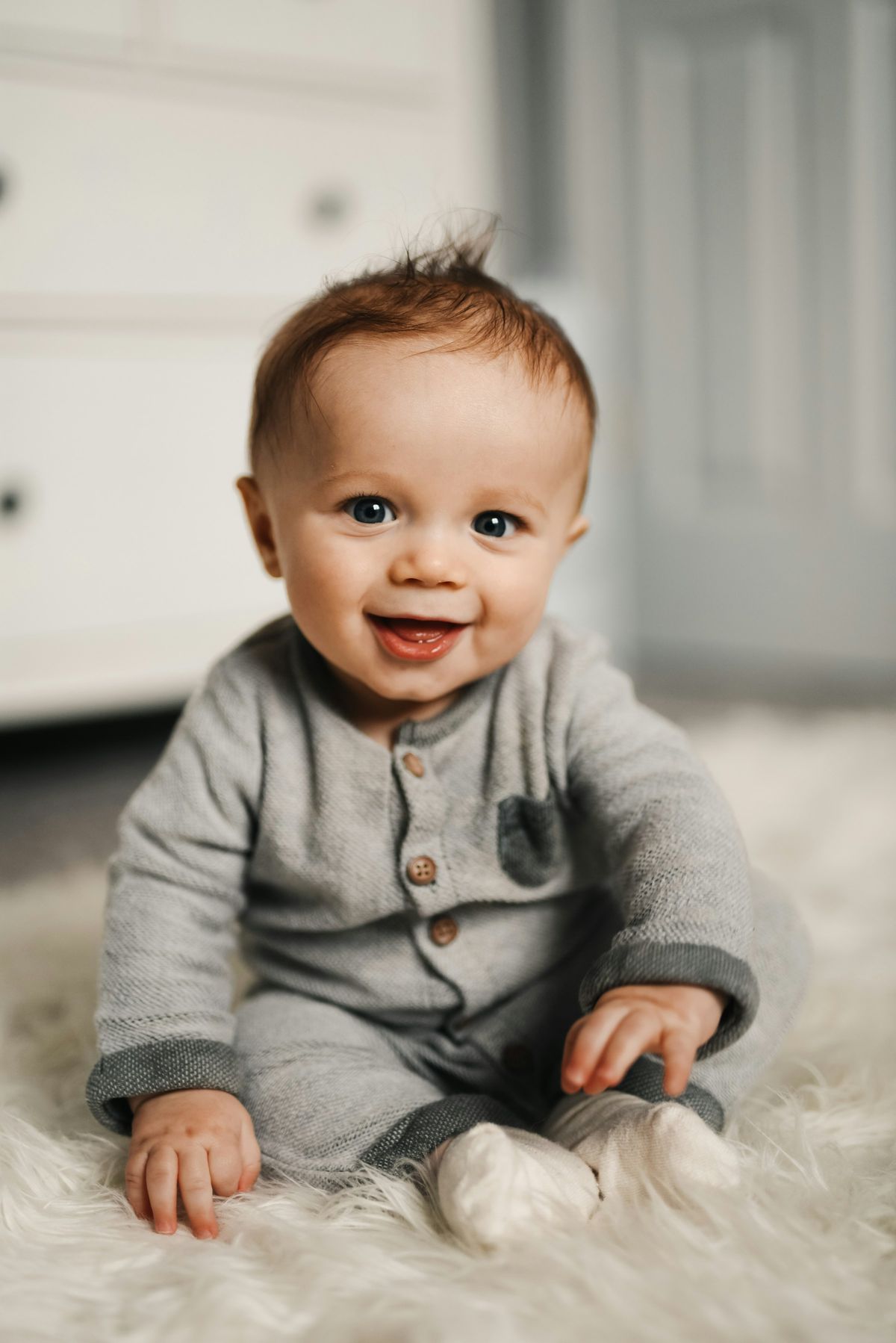A smiling baby in a soft grey cardigan