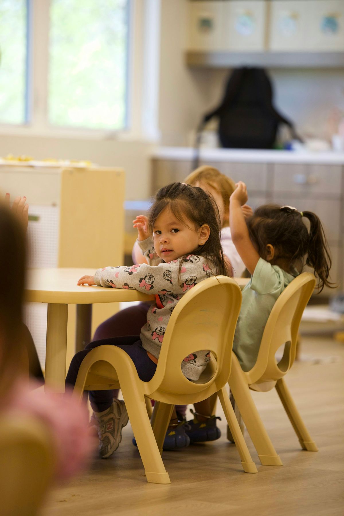 Preschoolers seated at a small table in a bright classroom