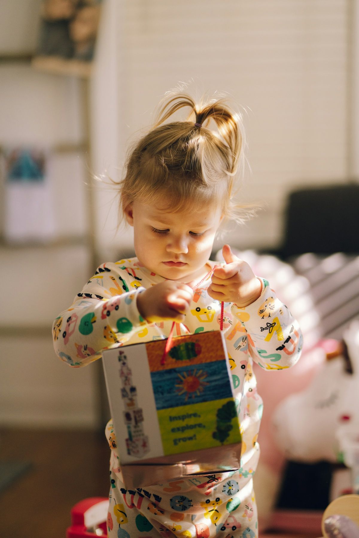 A toddler concentrating on opening a colorful toy box